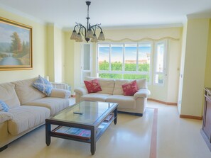 A living room with a sofa, a glass coffee table, and a chandelier. - Neptuno Apartment in Estepona, 3 bedrooms, air conditioning (Estepona)
