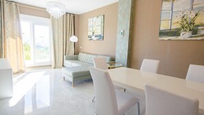 Een moderne woonkamer met een eethoek, een groot raam en een kroonluchter.