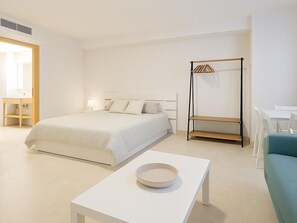 A minimalist hotel room with a bed, bedside table, and a small table with a bowl. - Beachfront Studio in Estepona, sleeps 4, with air conditioning (Estepona)