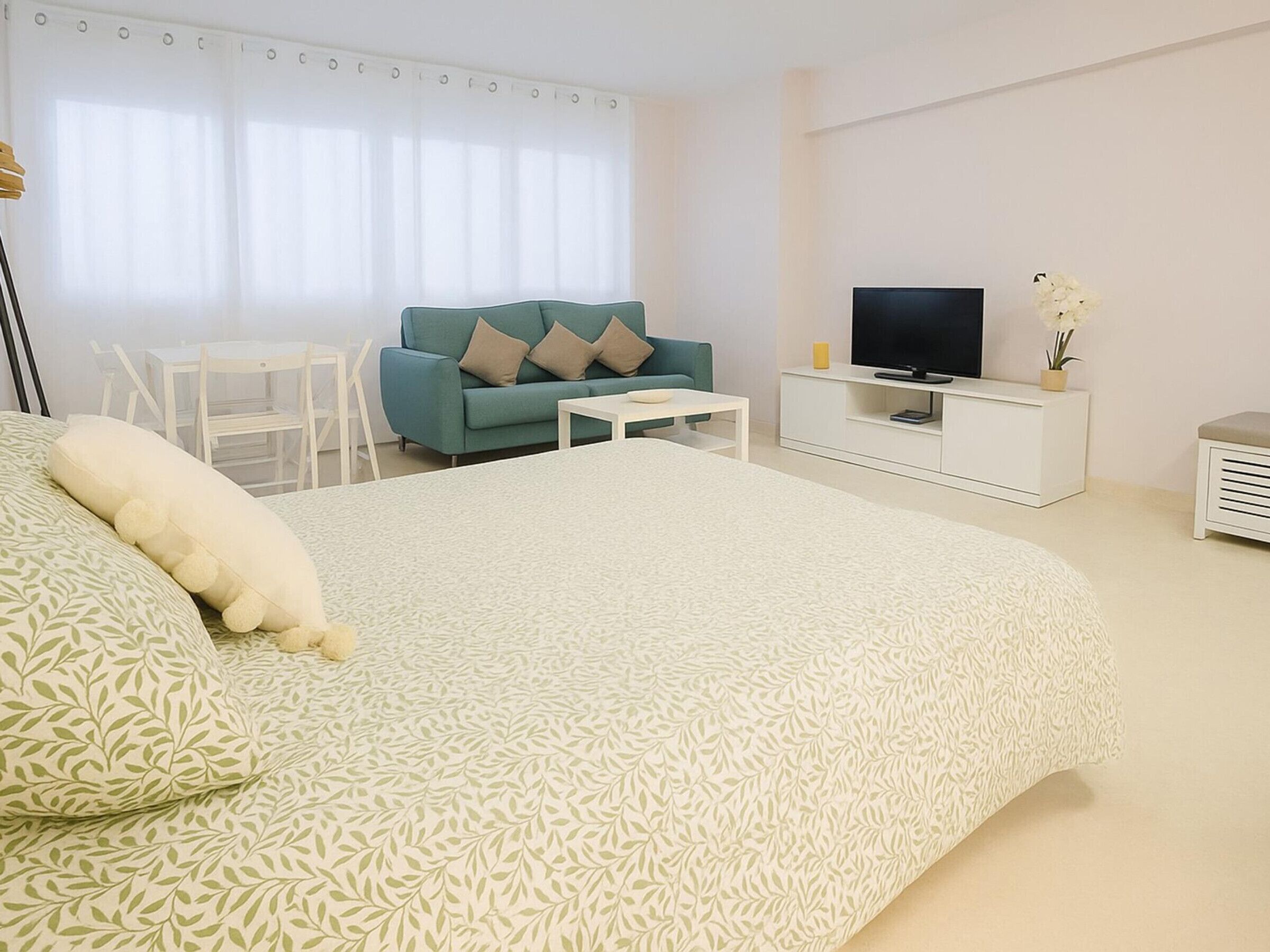 Un dormitorio con una cama grande, televisor, sofá y una mesita.