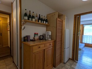 Eine kleine Küche mit Holzausstattung, einer Kaffeemaschine und einem Weinschränkchen.