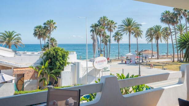 Ein Balkon mit Blick auf den Strand, Palmen und einem Schild für Alahardeno.