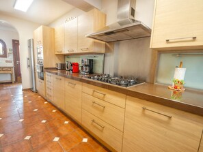 Una cocina moderna con armarios de madera, electrodomésticos de acero inoxidable y piso de baldosas.