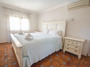 Una habitación de hotel con cama, mesita de noche, cómoda y ventana con cortinas.