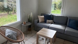A living room with a grey sofa, a wooden coffee table, a wicker chair, and a small side table with a vase.