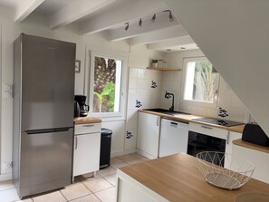 A modern kitchen with a stainless steel refrigerator, white cabinets, a wooden countertop, and a window with a view of greenery. - Cozy house, pets welcome - 6 guests (Bangor)