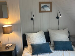 A bedroom with a bed, two wall-mounted lamps, a framed fish picture, a bedside table with a lamp, and a mirror. - Cozy house, pets welcome - 6 guests (Bangor)