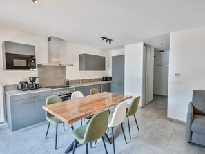 Eine moderne Küche mit Essbereich, inklusive Holztisch und -stühlen, einem eingebauten Backofen und einer Mikrowelle.
