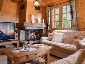 Ein gemütliches Blockhäuschen mit Kamin, Holzmöbeln und einem Fernseher.