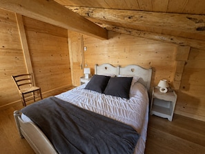 Una habitación de madera con una cama, una silla y una mesita de noche.