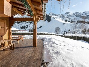 A wooden deck with benches, a snow-covered landscape, and a mountainous backdrop. - 4★ chalet, pets allowed, 9 guests, panoramic view (La Clusaz)