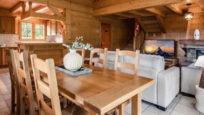 Ein Holzinterieur mit einem Esstisch, Stühlen, einer Couch und einem Kamin.