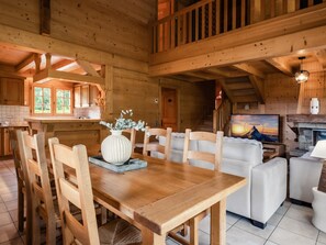 A wooden interior with a dining table, chairs, a sofa, and a fireplace. - 4★ chalet, pets allowed, 9 guests, panoramic view (La Clusaz)