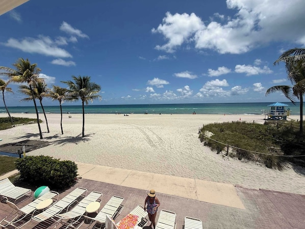 Ein Strand mit Liegestühlen, Palmen und einem Rettungsturm.