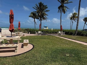 Een resortgebied met terras, palmbomen en uitzicht op de oceaan.