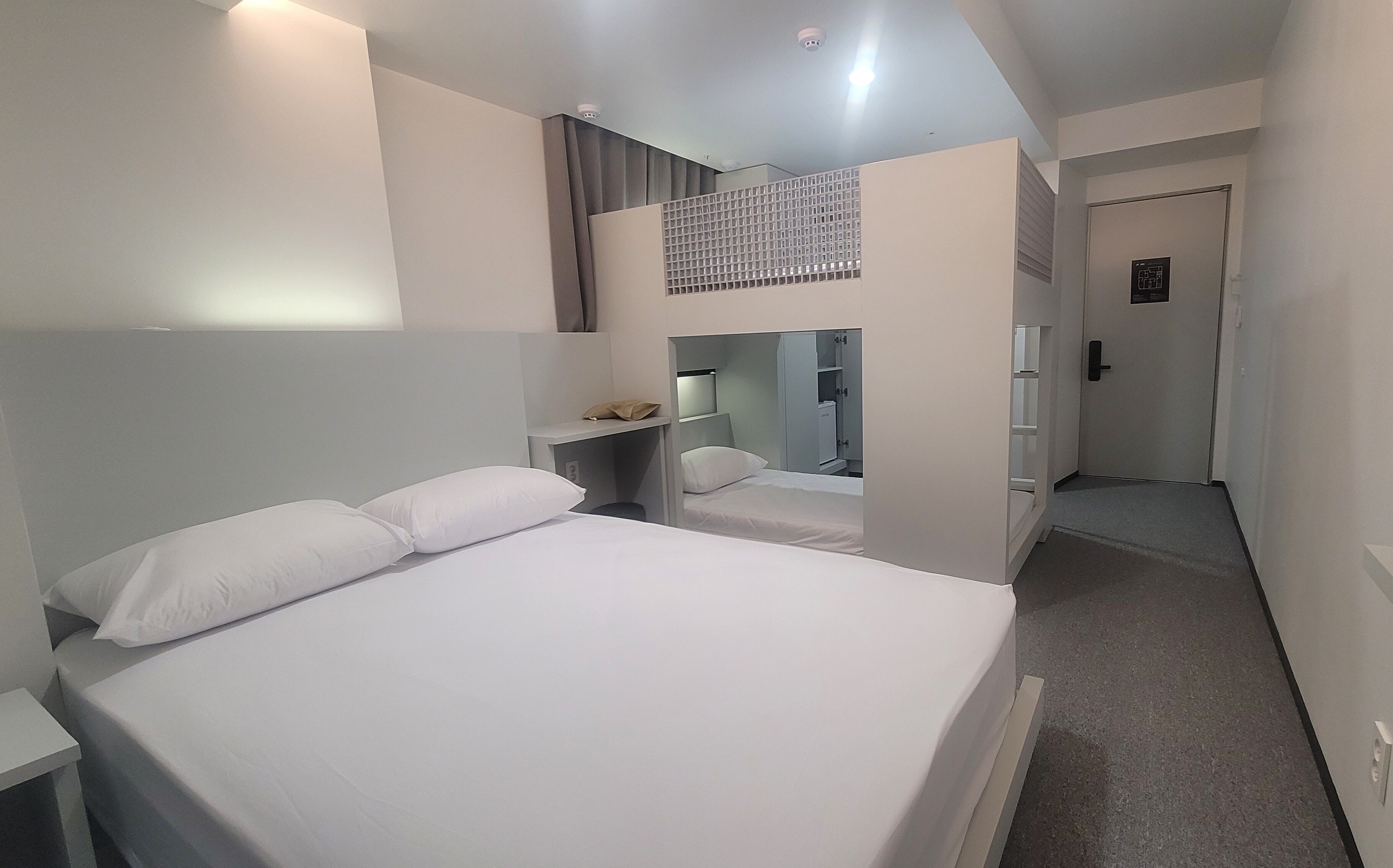 A hotel room with a bed, a desk, a wardrobe, and a mirror.
