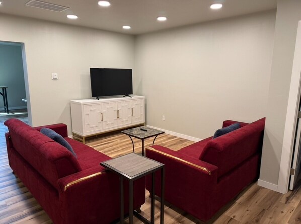 A living room with a TV, white cabinets, red sofas, and a small table.