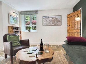A cozy living room with a stone floor, a wooden coffee table, a leather armchair, a sofa, and a wooden cabinet. - Glen Cottage, Porlock (Porlock)
