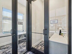 Quarto de hotel moderno com foco na privacidade, apresentando uma porta de vidro com puxador, uma placa indicando o tipo de quarto e um vislumbre da vista externa pela janela.