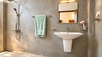 A modern bathroom with a shower, sink, and towel rack.