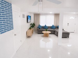 Una sala de estar moderna con un sofá seccional, una mesa de centro, un televisor y una planta.