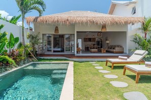 Ein modernes Haus mit Pool, Außenbereich und einem Strohdach.