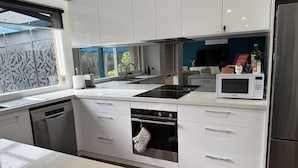 A modern kitchen with white cabinetry, a built-in oven, a microwave, and a dishwasher. - CountrysideRetreat Romance Luxury Cottage NativeWildlife Daylesford – Hepburn (Hepburn)