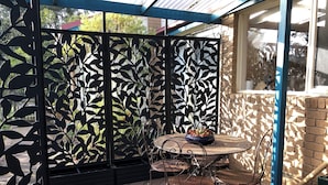 A patio with a metal table and chairs, a decorative black fence, and a brick wall. - CountrysideRetreat Romance Luxury Cottage NativeWildlife Daylesford – Hepburn (Hepburn)