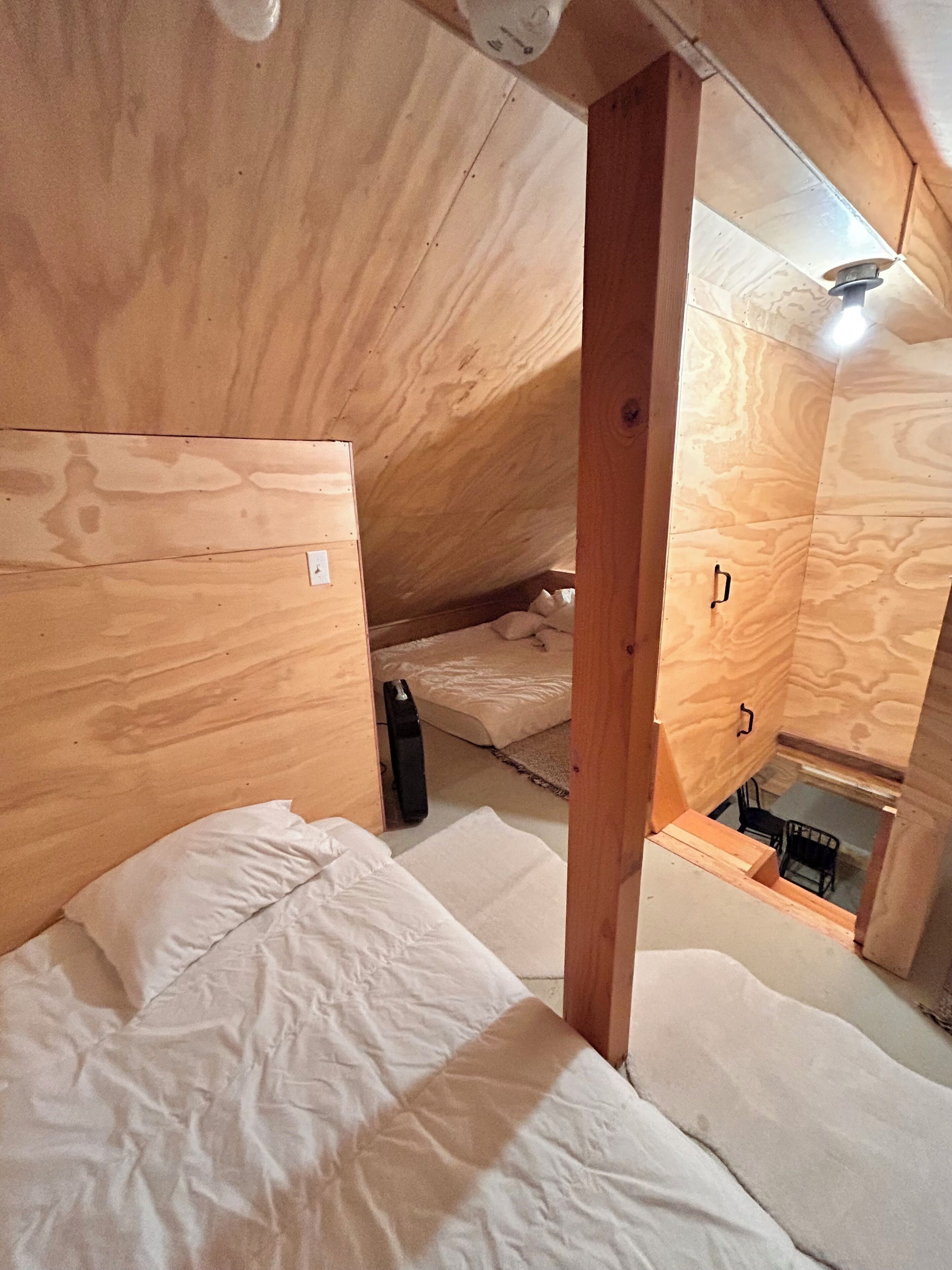 Un interior de madera con una cama, una mesita y una silla.