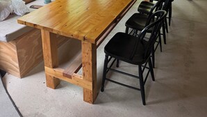 Un interior de madera con una mesa larga, sillas, ventanas grandes y una decoración con forma de oso en la pared.