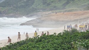 A beach with rocky terrain and vegetation in the foreground. - Beachfront apartment with ocean view in Recreio. (Rio de Janeiro)