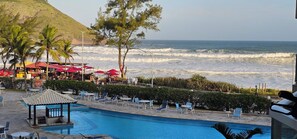 Un espace aménagé au bord de la piscine, avec des chaises longues, des parasols et une vue sur l’océan.