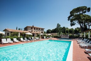A swimming pool with lounge chairs and umbrellas, surrounded by buildings and trees. - Pomaia - Two Bedroom (Santa Luce)