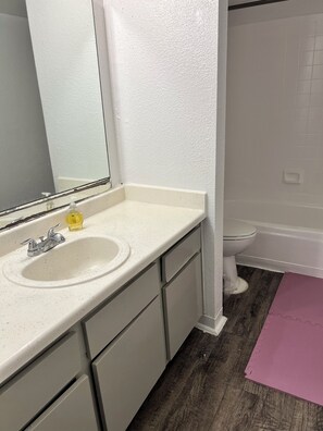 Un baño con lavamanos blanco, espejo y retrete.