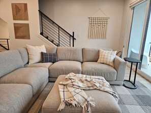 Ein Wohnzimmer mit Ecksofa, Decke, Treppe und Wandgestaltung.