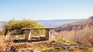 Un banc de pierre sur une colline rocheuse, d’où l’on a vue sur une vallée boisée.