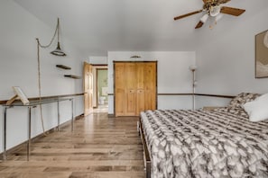 A bedroom with a wooden wardrobe, a bed with a patterned blanket, a ceiling fan, and a hallway leading to a bathroom. - Maison familiale Charlesbourg, Spa (Québec)