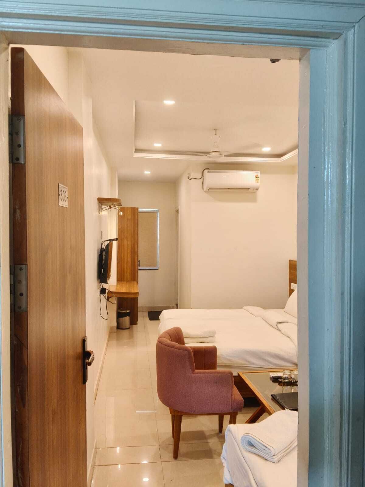 Una habitación de hotel con una cama, una silla, un escritorio y un espejo.