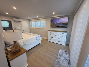 Une chambre à coucher avec un lit, une lampe de chevet, une commode et un tableau au mur.
