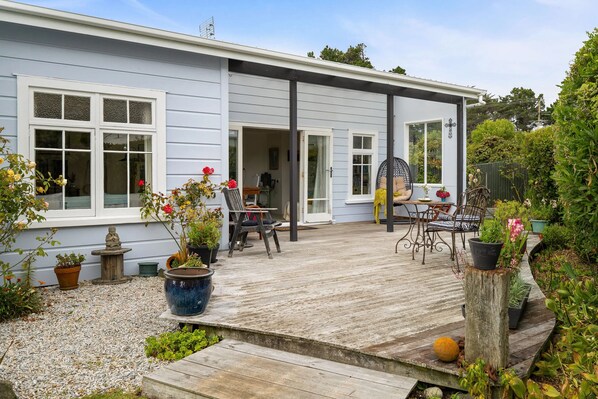 Ett hus med en träveranda, en stenskulptur och krukväxter.
