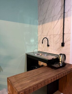Eine Küche mit Marmorfliesenspiegel, einem schwarzen Wasserhahn, einer Holz Arbeitsplatte und einem Wasserkocher.