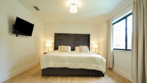 A bedroom with a bed, bedside lamps, a flat-screen TV, and a window with curtains. - World Cup Oasis. 12 min from Beach & Casino. 18 min from World Cup stadium. (Hollywood)