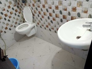 Un baño con inodoro, lavamanos y piso de baldosas.