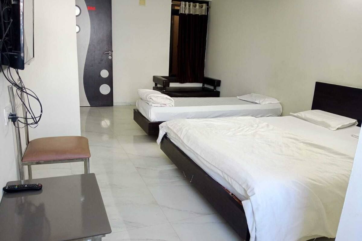 Habitación de hotel con dos camas, un escritorio, una silla y un televisor.