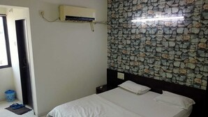 Un dormitorio con cama, aire acondicionado, pared con diseño y una puerta.