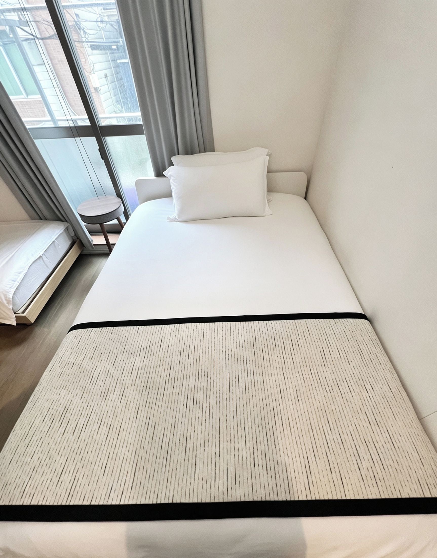 Una habitación de hotel con cama, una mesita y ventana con cortinas.
