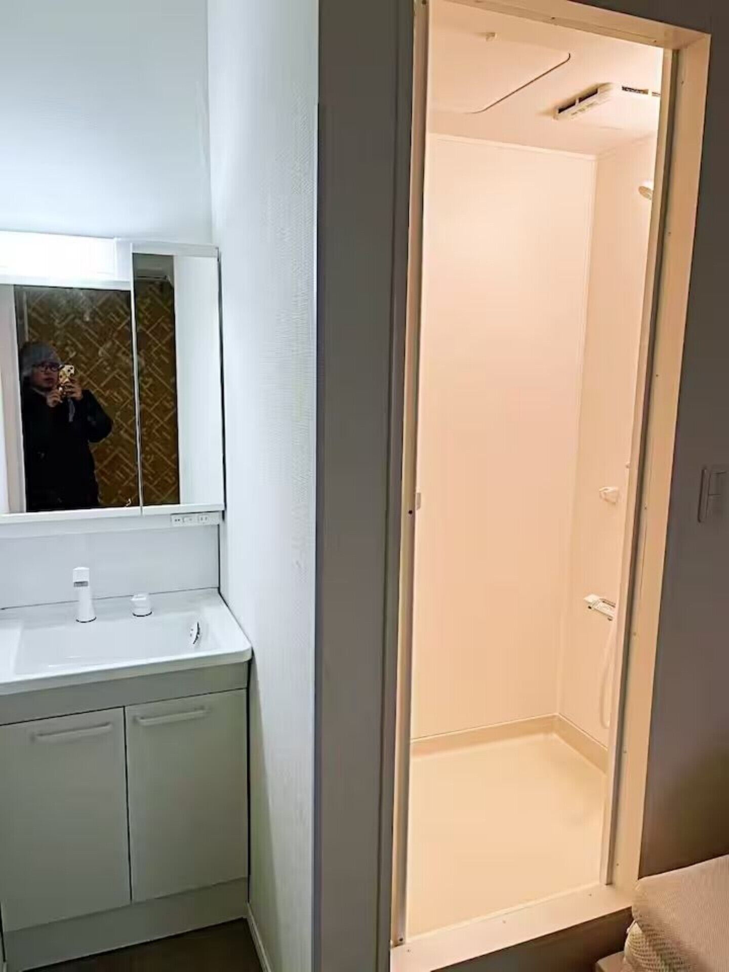 A bathroom with a mirror, sink, and shower.