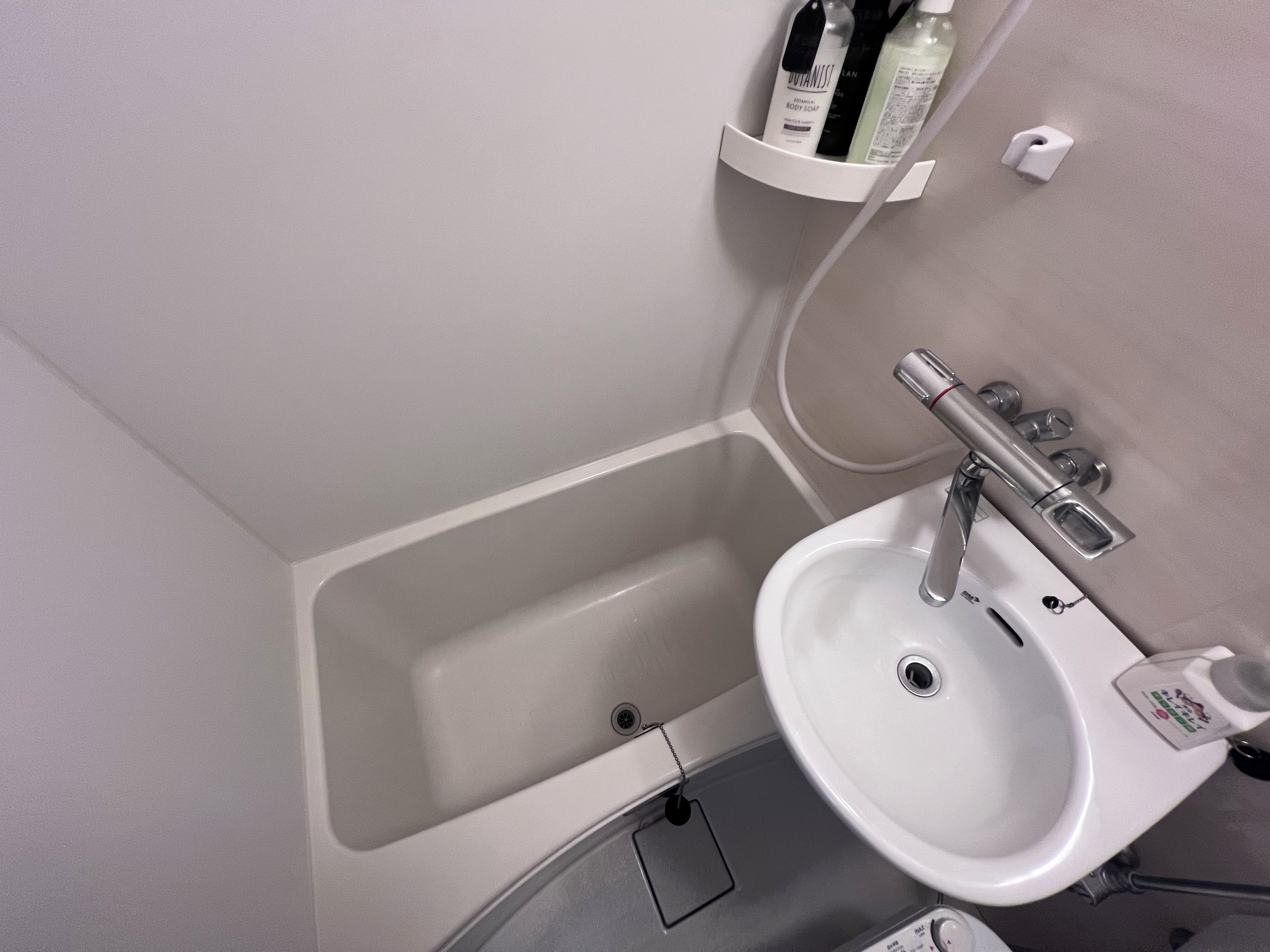 Un baño con una bañera, un lavamanos y un estante con artículos de aseo.