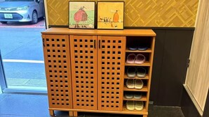 Un porte-chaussures en bois avec plusieurs étagères, un extincteur et un véhicule à l’extérieur.