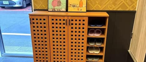 A wooden shoe rack with multiple shelves, a fire extinguisher, and a vehicle outside.